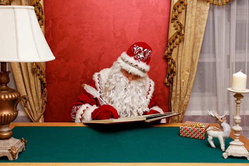 Santa Claus write on the  book sitting at the table. Copyspace.