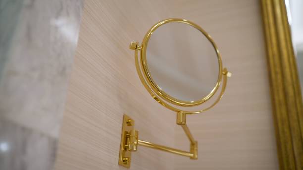 istock New bathroom with pattern wallpaper, sparkle floor, round mirror with decorative golden frame and black basin. A round, golden mirror in the bathroom. 1290970567