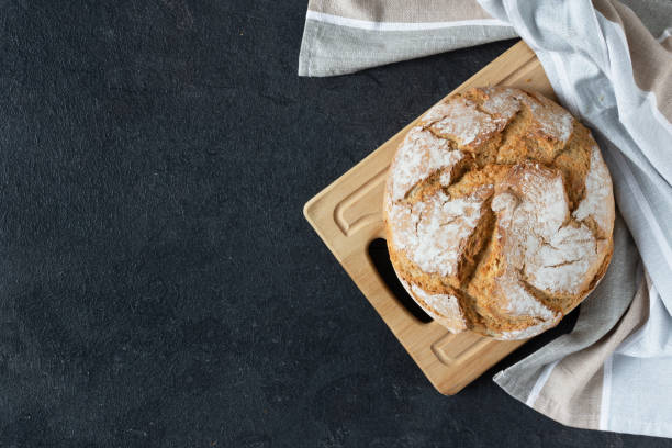 istock Loaf of sourdough bread with crispy crust on black background top view. 1290972293