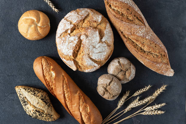 istock Assortment of baked bread and buns on black background top view. 1290972305
