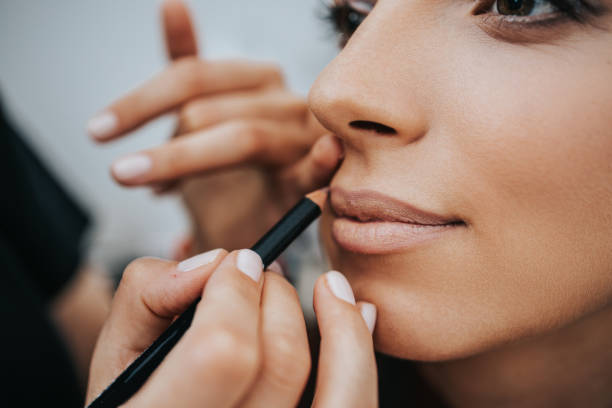 istock Make up artist with face protective mask applying professional make up of beautiful middle age brunette  woman. Coronavirus pandemic lifestyle. 1290972368