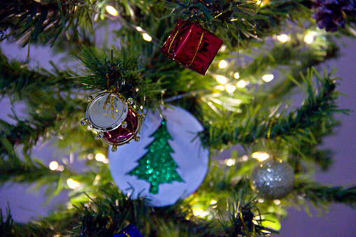 Christmas balls, fir tree branches and Christmas ornament, Background of fluffy branches green color New Year trees decorated with beautiful golden shiny sphere balls, toys and ornates.
