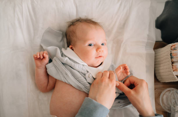 istock top view. mom's hands put a jumpsuit on the baby 1290972533