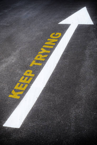 istock Keep trying words with arrow sign marking on road surface 1290973334