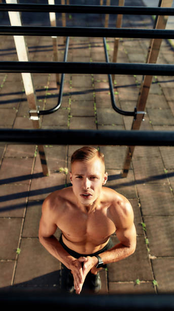 Young caucasian athlete looking up on training apparatus