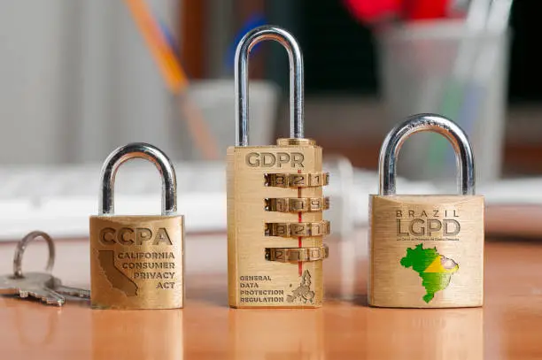 Photo of Data protection laws concept: three locks shows the names of three data protection laws: california consumer privacy act, general data protection regulation and lei geral de proteção de dados pessoais (ccpa, gdpr, lgpd)