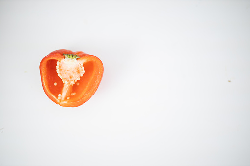 Half a red bell pepper isolated on white table. Above view of fresh sliced vegetable on white surface. Healthy meal preparation