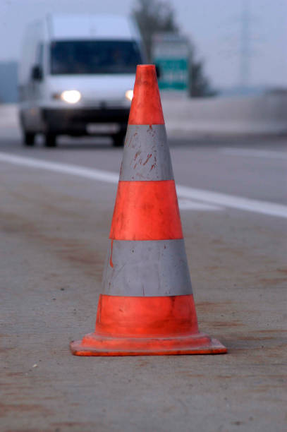 istock Road safety: traffic cone in front and car headlights in the back 1290981004