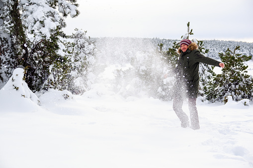Seasonal, snowy weather concept - young man kicks snow on the deep snowdrifts.
