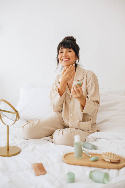 istock Smiling woman using beauty cosmetics at home 1290985753