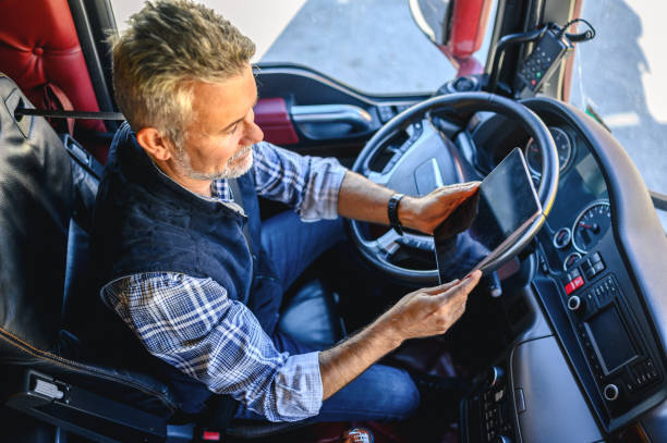 motorista de caminhão usando um aplicativo móvel - truck truck driver trucking semi truck - fotografias e filmes do acervo