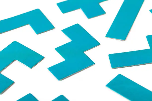Photo of Various shapes, blue puzzle elements, pattern, white background abstract. Scattered unorganized parts, simple different unlinked disconnected figures, no connection, solving problems abstract concept