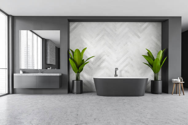 istock Modern grey bath and sink with mirror in a big bathroom with grey floor 1290994354