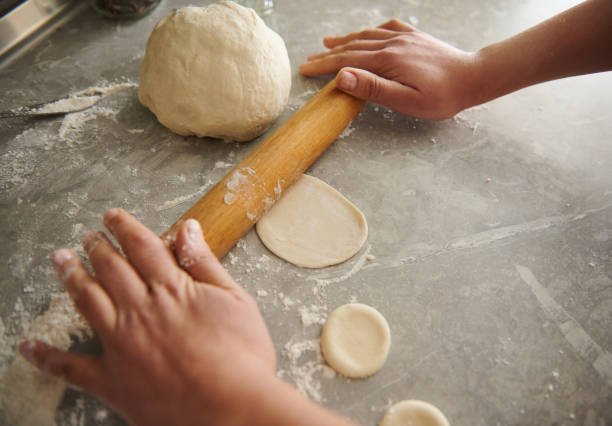 istock Close up of woman's hands rolling out the dough in the kitchen 1291004347