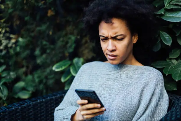 Photo of Young African American woman reading bad news on her mobile device