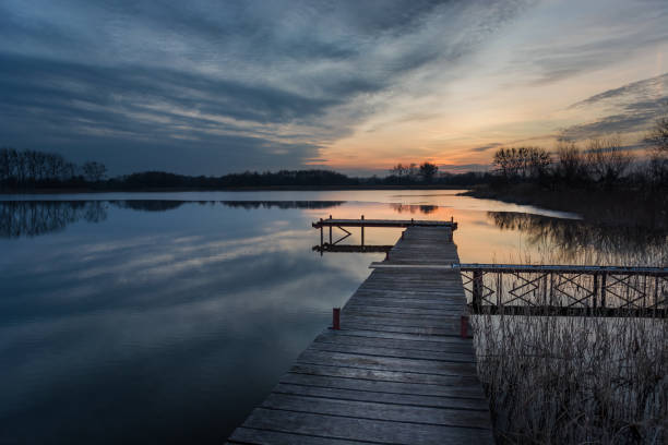 istock Long wooden bridge on the lake and sunset clouds 1291007320