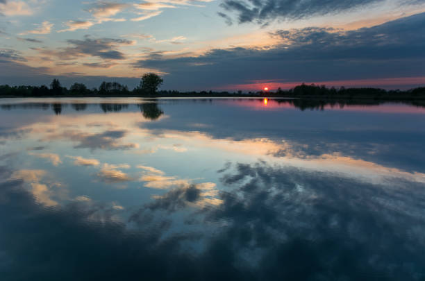 istock Colorful clouds reflected in the calm lake at sunset 1291007323