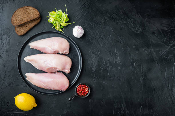 istock Raw crumbet chicken fillet with ingredients, on black background, flat lay  with copy space 1291007380