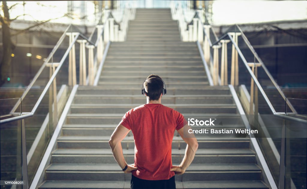 Man in red shirt preparing for stair run. Man in red shirt preparing for stair run at sunset. Motivation Stock Photo