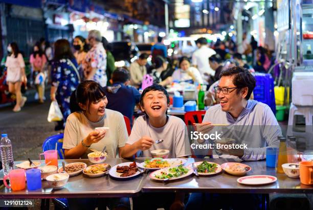 Asian Family Enjoy Eating Food On Street Food Restaurant With Crowd Of People At Yaowarat Road Bangkok Stock Photo - Download Image Now