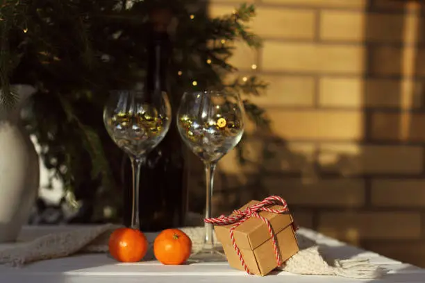 a gift tied with a striped cord on a table with a scarf and tangerines against the backdrop of a festive setting