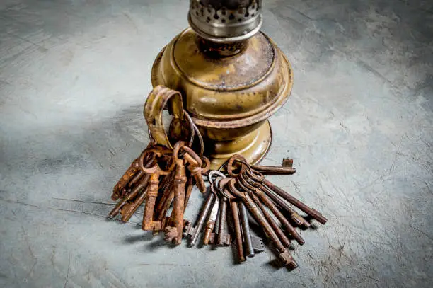 A bunch of rusty keys hang from the handle of an old lamp.