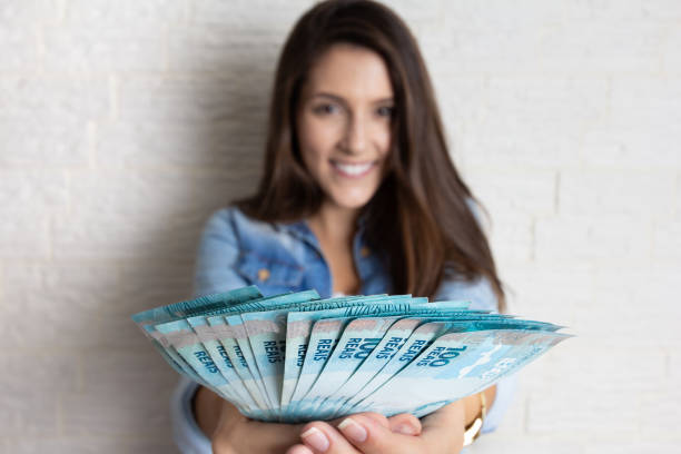 woman holding brazilian banknotes currency - reduction looking at camera finance business imagens e fotografias de stock