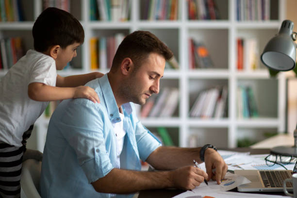 istock an working from home with laptop during quarantine. Home office and parenthood at same time. Exhausted parent with hyperactive child. 1291018362