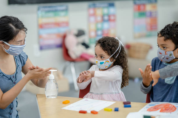 istock Daycare educator showing students how to hand sanitize 1291018554