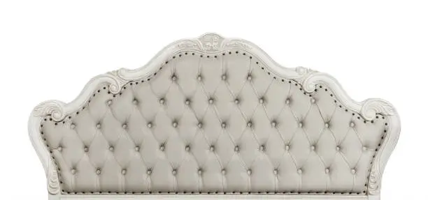 Shaped pastel beige color soft tufted leather capitone bed headboard of Chesterfield style sofa with carved wooden frame, isolated on white background, front view