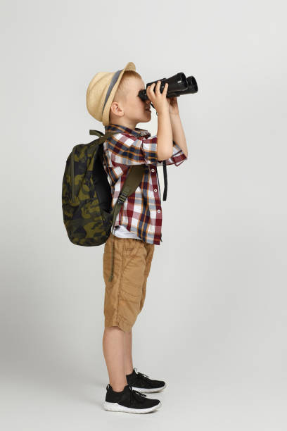 istock Little boy tourist with backpack looking through a binoculars. 1291028215
