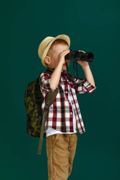 istock Little boy tourist with backpack looking through a binoculars. 1291030380