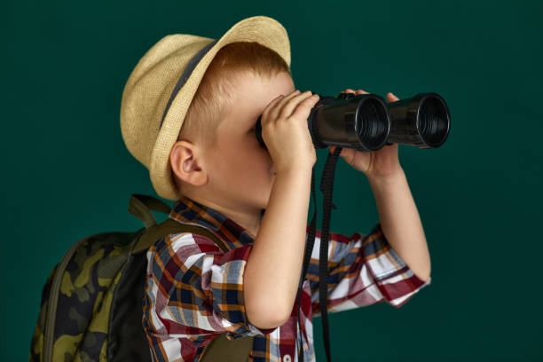 istock Little boy tourist with backpack looking through a binoculars. 1291030383