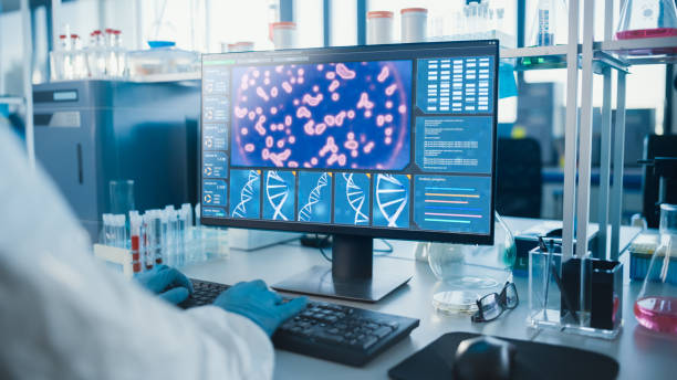 istock Advanced Laboratory: Medical Scientist Working on Personal Computer Developing Vaccine, Drugs and Antibiotics. Screen Shows High-Tech Concept for DNA research. Focus on Screen and Hands 1291031181