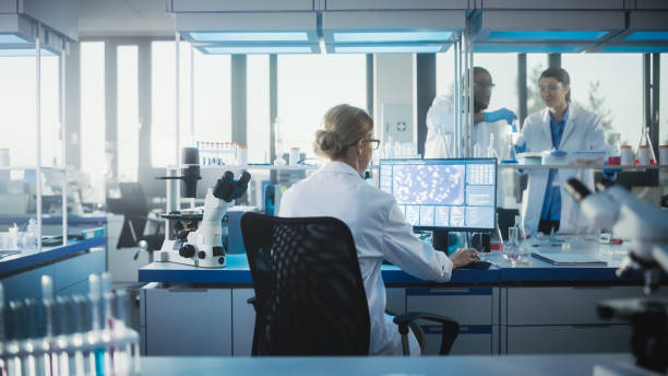 laboratorio medico con team di scienziati che lavorano. microbiologist is using personal computer, screen shows high-tech concept per la ricerca sul dna. ricerca biotecnologica ad alta tecnologia. scatto vista posteriore - dna molecular structure genetic research biotechnology foto e immagini stock