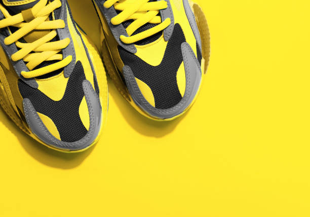 istock Multicolor sport shoes on yellow background with shadows 1291031698