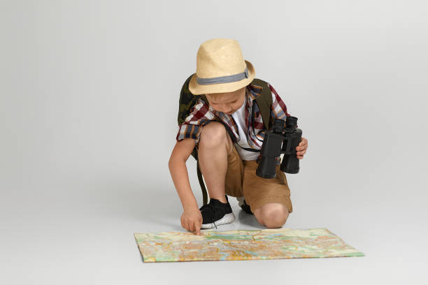 pequeño turista niño con mochila sosteniendo binoculares y mapa. - discovery binoculars boy scout searching fotografías e imágenes de stock