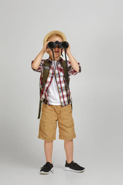 pequeño turista con mochila mirando a través de un binocular. - discovery binoculars boy scout searching fotografías e imágenes de stock