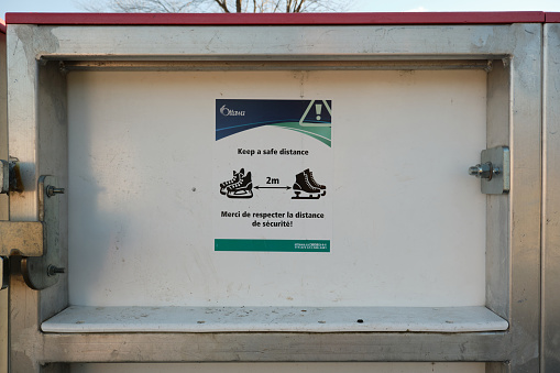 Ottawa, Canada.   December 9. 2020. Public health sign during Covid Pandemic on skating rink telling to stay two meters appart with image of skates