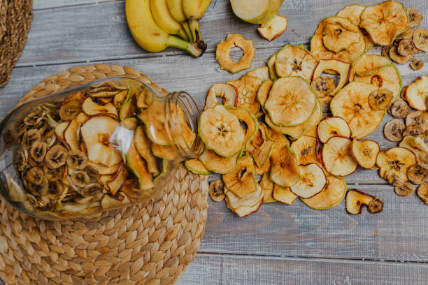 istock Apple fruit chips in the jar with fresh fruits on the wooden table. Chips for fruit leather. Healthy food. Apples, bananas top view. 1291035346