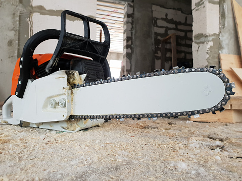 chainsaw is strewn with sawdust on the floor in country house under construction of foam blocks