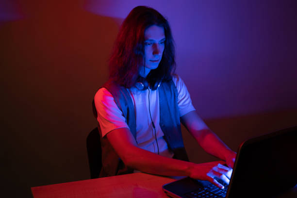 istock Student or programmer at a laptop, portrait in neon tinting. Funny guy geek writes code. 1291037556