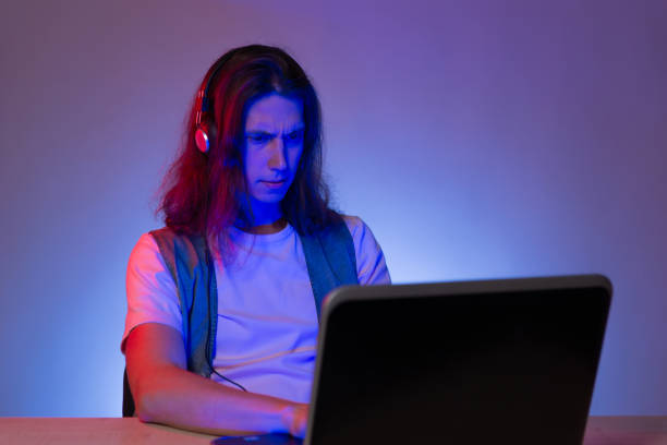 istock Student or programmer at a laptop, portrait in neon tinting. Funny guy geek writes code. 1291037623
