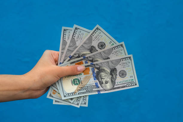istock Businesswoman with dollars isolated on blue 1291037778