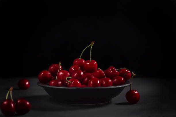 istock Cherries in a black plate on a black background. 1291044085