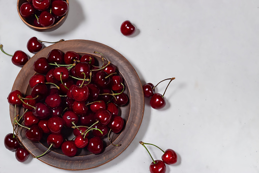 Ripe sweet cherries on a brown plate on a white background. View from above.