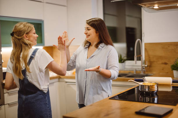 istock Two smiling caucasian women giving high five in the kitchen 1291044469