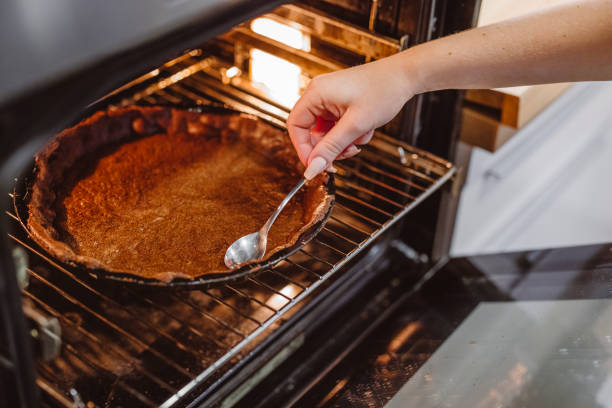 istock Woman hand reaching into the oven testing is the crust is baked 1291044475