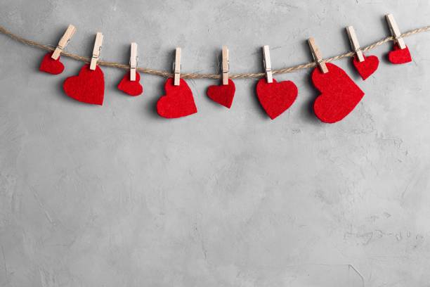Red hearts on rope with clothespins, on a grey background Red hearts on rope with clothespins, on a white grey concrete background. Place for text, copy space. february stock pictures, royalty-free photos & images