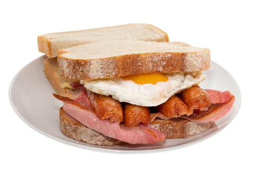 A breakfast sandwich of grilled sausage and bacon with a fried egg - white background